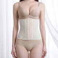 A model wearing a beige underwire bra, a beige waist trainer corset with a mesh pattern and center button closure, and matching beige high-waisted briefs, set against a soft white curtain background.