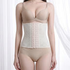 A model wearing a beige underwire bra, a beige waist trainer corset with a mesh pattern and center button closure, and matching beige high-waisted briefs, set against a soft white curtain background.