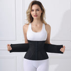 A woman modeling a black waist trainer belt with built-in sleeves, shown against a white paneled wall background.
