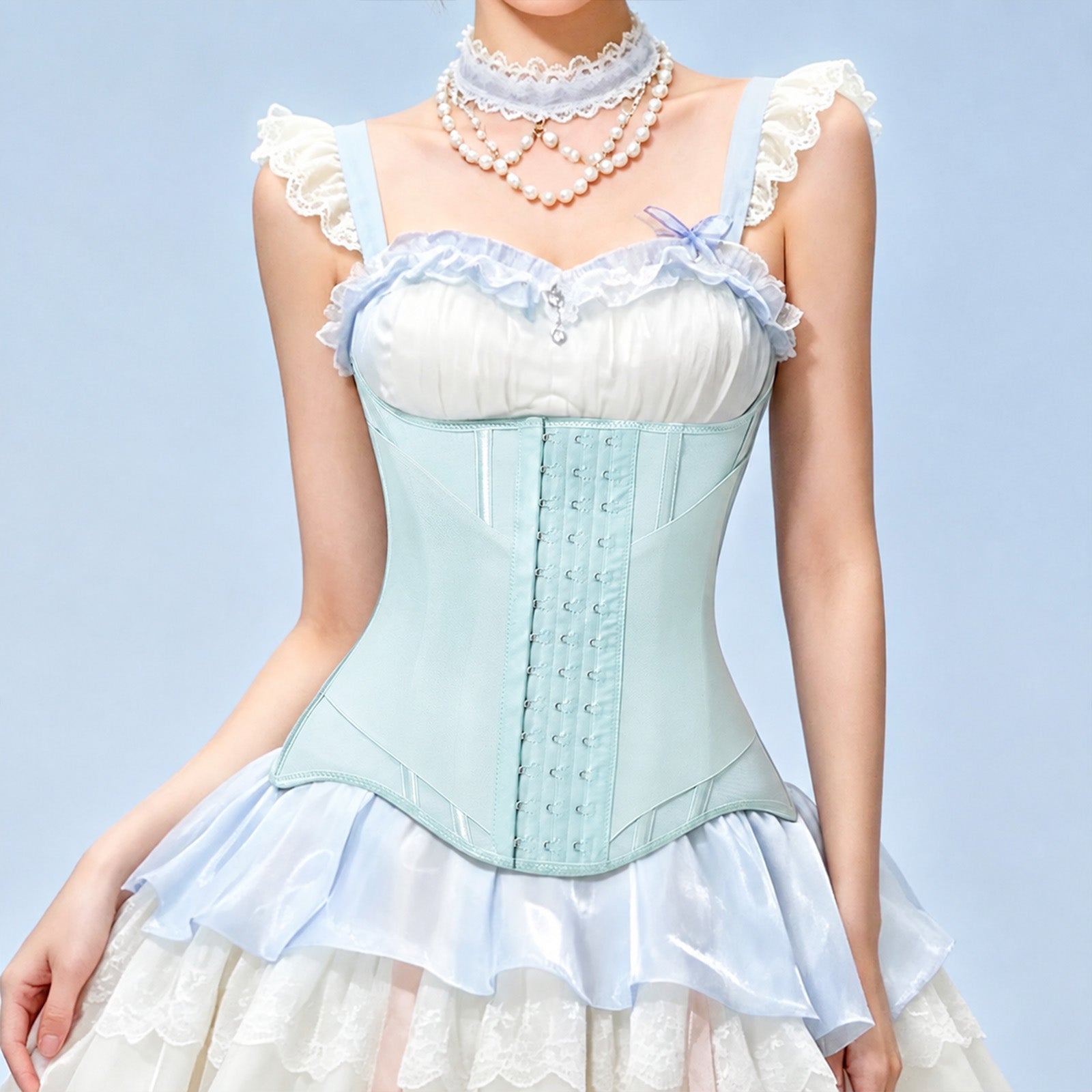 A model wearing a light blue and white corset-style dress top with ruffled straps, lace trim, a pearl choker, and a matching ruffled skirt against a pale blue background.