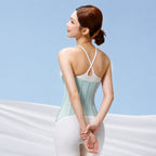 A woman shown from the back wearing a light mint green and white waist trainer corset top with white leggings, set against a light blue background with draped white fabric.