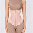 A model wearing a light pink waist trainer corset over matching nude-colored shapewear, shown from the chest down against a light gray background.