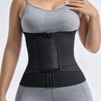 A black waist trainer belt with a front zipper and a large rectangular patch pocket, shown worn by a model in a gray sports bra and leggings against a light gray studio background.
