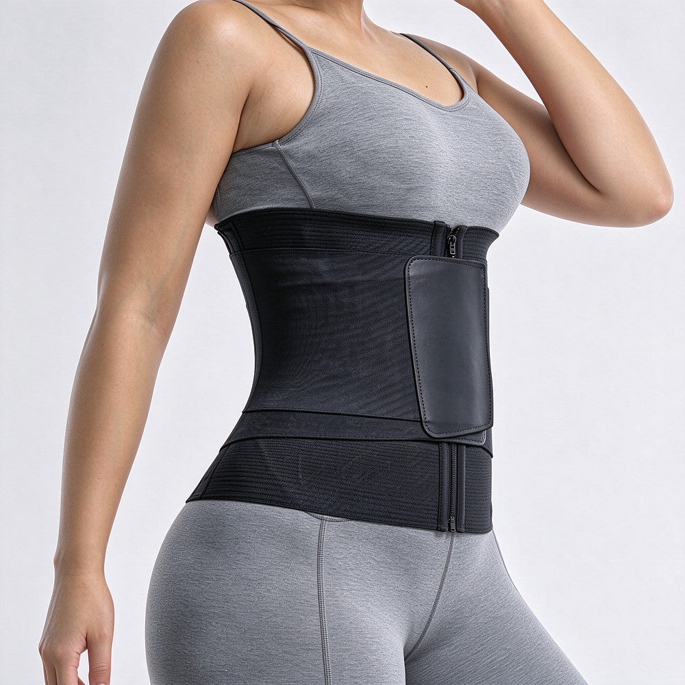 A woman wearing a black waist trainer belt with a front zip closure and a side pocket, paired with gray athletic wear, shown against a light gray studio background.