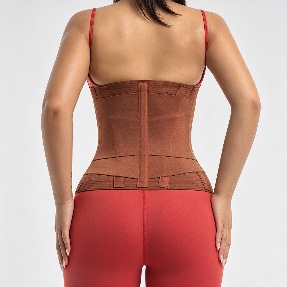 Rear view of a woman wearing a brown waist trainer corset with a center back zipper, paired with red leggings, against a light gray background.