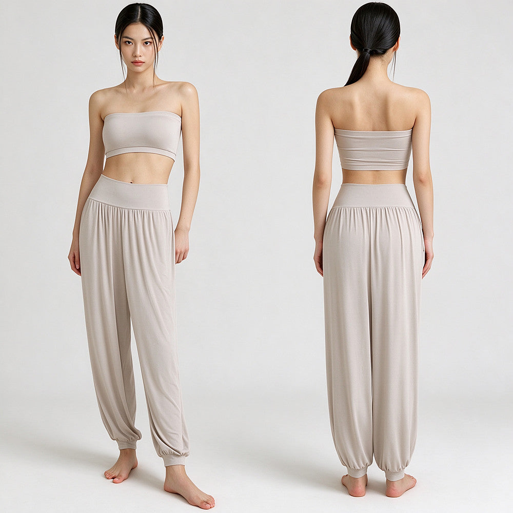 A model is shown from the front and back wearing a matching beige two-piece lounge set consisting of a bandeau-style crop top and high-waisted harem pants, against a plain light gray studio background.