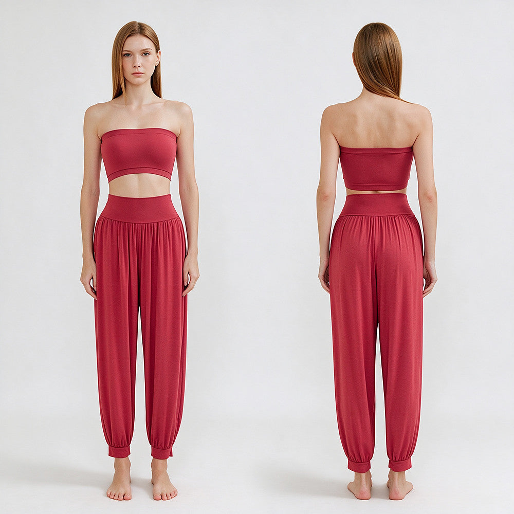 A model is shown from the front and back wearing a matching two-piece lounge set in a dusty rose red color. The set includes a strapless bandeau-style crop top and high-waisted, loose harem-style pants with elastic cuffs.