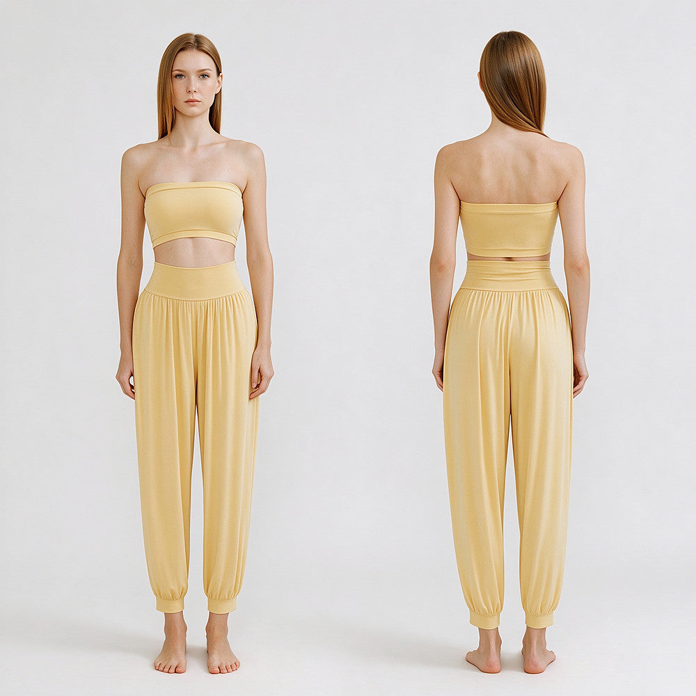 A model is shown from the front and back wearing a pale yellow two-piece lounge set consisting of a strapless bandeau-style crop top and matching high-waisted harem pants, against a plain light gray studio background.