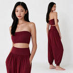 A model is shown in a studio setting wearing a two-piece maroon set consisting of a strapless crop top and matching high-waisted harem pants. The image features two views: a close-up front view on the left and a full-body rear view on the right, against a clean white background.