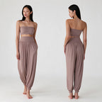 A model is shown from the front and back wearing a two-piece lounge set consisting of a strapless bandeau crop top and matching high-waisted, loose harem pants in a dusty mauve color, set against a plain light gray studio background.