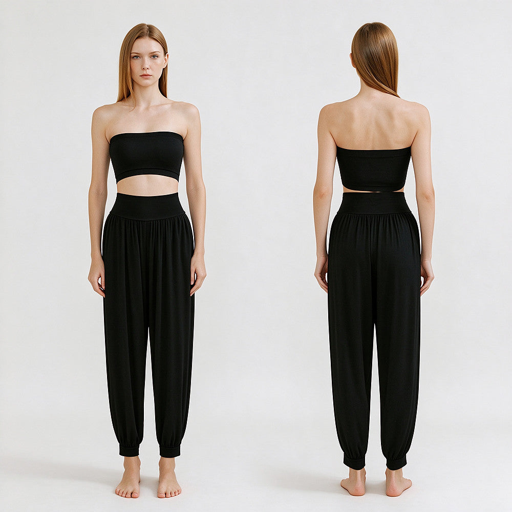 A model is shown from the front and back wearing a black two-piece outfit consisting of a strapless bandeau-style crop top and high-waisted loose harem pants, against a plain light background.