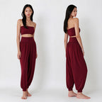A model is shown from the front and back wearing a matching two-piece outfit consisting of a strapless maroon crop top and high-waisted harem pants, set against a plain white studio background.