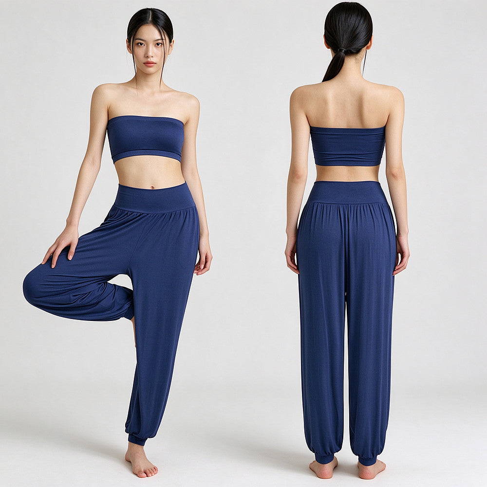 A two-piece navy blue activewear set shown on a model from both front and back views. The set includes a strapless bandeau-style crop top and matching high-waisted, loose harem-style pants with elastic cuffs.