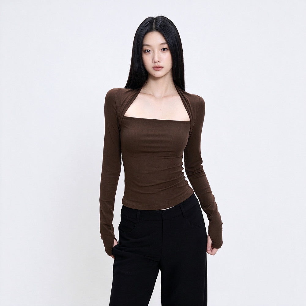 A woman modeling a fitted long-sleeve brown top with a square neckline and black pants, standing against a plain light gray studio background.