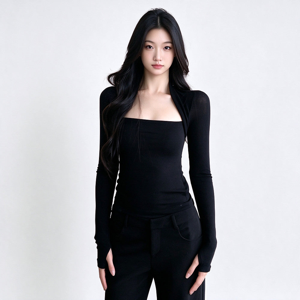 A woman modeling a black long-sleeve knit top with a square neckline and matching black pants against a plain light gray studio background.