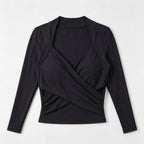 A black long-sleeve wrap-style top with a draped crossover front and open neckline, shown flat against a light gray background.