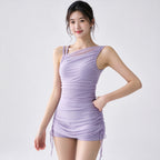 A woman modeling a lavender one-shoulder ruched mini dress with side drawstrings, photographed against a clean light gray studio background.